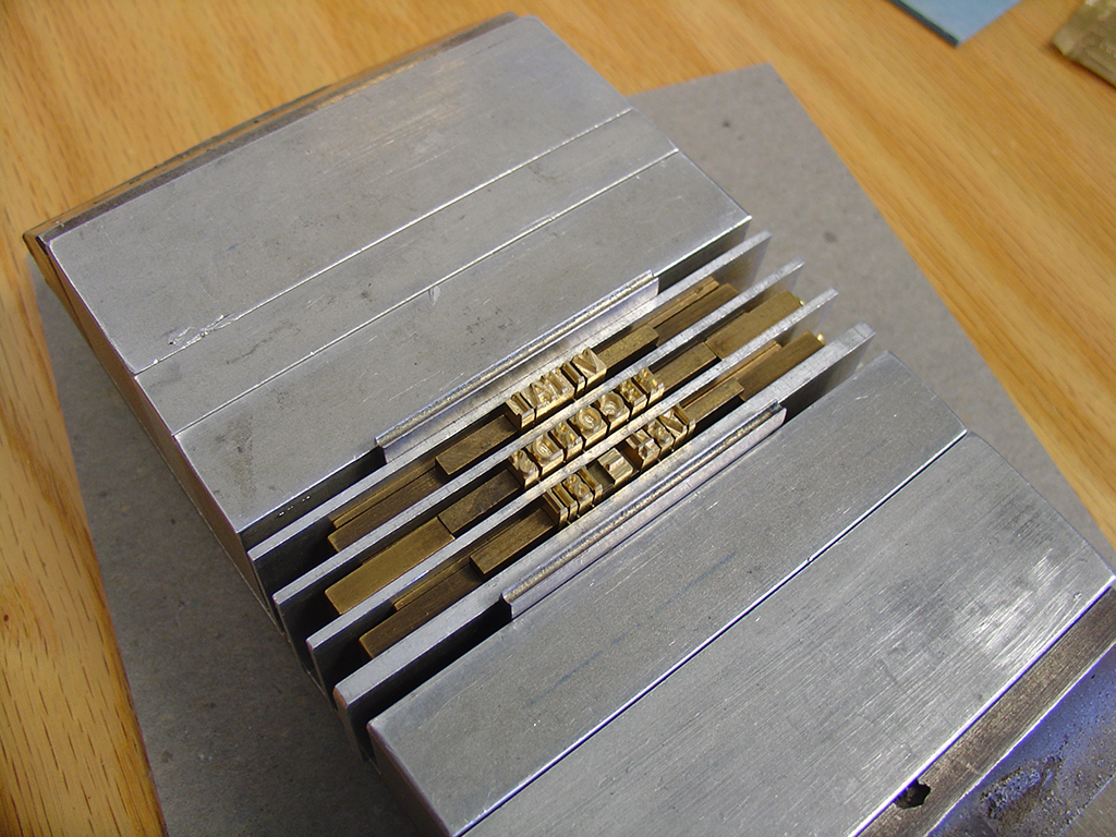 Brass type is set by hand to produce a gold-stamped leather label for the spine of the volume.